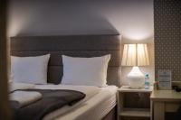 a bed with white pillows and a table with a lamp at So&sol boutique Hotel, Tuzla in Tuzla