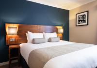 a bedroom with a large white bed with a wooden headboard at Toby Carvery Exeter M5 J30 by Innkeeper&#39;s Collection in Exeter
