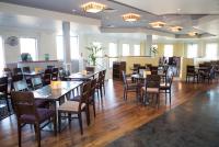 uma sala de jantar com mesas e cadeiras de madeira em Holiday Inn Slough Windsor by IHG em Slough