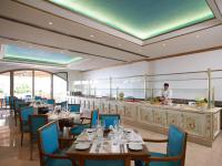 un restaurante con mesas y sillas y un chef en la cocina en Mitsis Selection Laguna, en Hersonissos