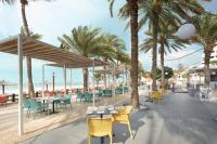 a restaurant with palm trees and tables and chairs at Occidental Sharjah Grand in Sharjah