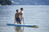 a man and a girl standing on a surfboard in the water at Ikos Dassia in Dassia