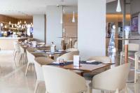 Un restaurante con mesas de madera y sillas blancas. en The Grand Hotel, en Punta del Este