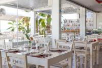 Un restaurante con mesas y sillas blancas y ventanas. en Island Boutique Hotel, en Lárnaca