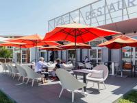 a group of people sitting at tables with umbrellas at Novotel Lyon Bron Meeting & Events in Bron