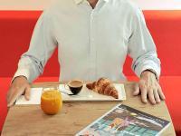 a man sitting at a table with a plate of coffee and croissants at ibis Paris Bastille Faubourg St Antoine in Paris