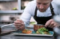 a man in a kitchen preparing a plate of food at Radisson Blu Scandinavia Hotel, Oslo in Oslo