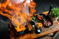 a person cooking food in a pan on a table at METROPOL Hotel Katowice in Katowice