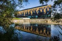 un edificio con un reflejo en un cuerpo de agua en MY HOME MY HOTEL Rosenheim, en Rosenheim