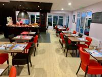a restaurant with wooden tables and red chairs at KYRIAD Issoudun in Issoudun