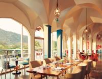 a restaurant with tables and chairs and large windows at Taj Devi Ratn Resort & Spa, Jaipur in Jaipur