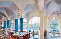 a dining room with tables and chairs and large windows at Taj Devi Ratn Resort & Spa, Jaipur in Jaipur