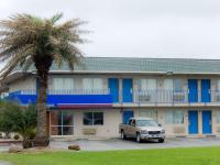 un camión estacionado frente a un edificio con una palmera en Motel 6-Clute, TX, en Clute