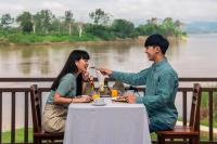 Ein Mann und eine Frau sitzen an einem Tisch und essen in der Unterkunft Bansaeo Garden and Resort in Chiang Saen