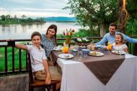 Eine Familie sitzt an einem Esstisch mit Blick auf einen Fluss in der Unterkunft Bansaeo Garden and Resort in Chiang Saen