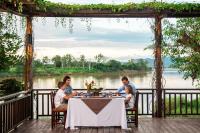 Eine Familie isst an einem Tisch mit Blick auf einen Fluss zu Abend. in der Unterkunft Bansaeo Garden and Resort in Chiang Saen
