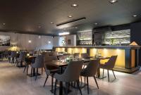 Un restaurante con mesas y sillas y un bar. en ProfilHotels Grand Kristianstad, en Kristianstad