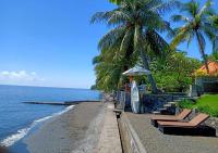 a beach with chairs and an umbrella and a surfboard at Mojito Beach Villas in Kubutambahan