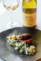 a plate with a piece of meat and a glass of wine at The Maltsters Arms in Totnes