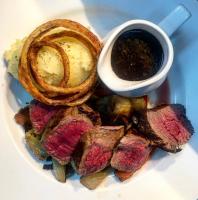 a plate of food with meat and onion rings and sauce at The Horseshoe & Castle in Rochester
