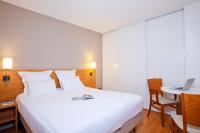 a bedroom with a bed and a desk with a laptop at Séjours &amp; Affaires Nantes La Beaujoire in Nantes