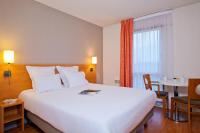 a hotel room with a large white bed and a table at Séjours &amp; Affaires Nantes La Beaujoire in Nantes