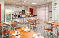 a restaurant with wooden tables and chairs and a kitchen at Séjours &amp; Affaires Nantes La Beaujoire in Nantes