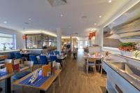 Un restaurante con mesas de madera y sillas azules. en Hotel Ostseewoge, en Graal-Müritz