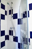 a bathroom with a shower with blue and white tiles at Hotel Luxor in Issy-les-Moulineaux