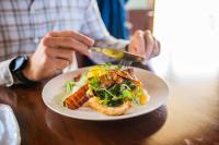 una persona sentada en una mesa con un plato de comida en Hotel Olivewood, en East London