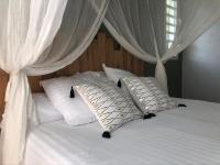 a white bed with white curtains and pillows on it at Gîte Maracudja vue sur mer in Capesterre-Belle-Eau