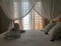 a bed with white curtains and a stuffed animal on it at Gîte Maracudja vue sur mer in Capesterre-Belle-Eau