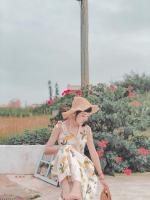 a woman in a dress and hat sitting in front of a bush at Minami Kaze in Magong