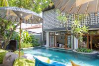una piscina con 2 sombrillas junto a una casa en Interconnection Hostel, en Kuta