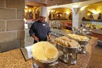 a chef standing in a kitchen preparing food at Holiday Inn Queretaro Centro Historico by IHG in Querétaro
