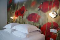 a bed with pillows and red flowers on a wall at L’Échappée Belle in LʼIsle-Jourdain