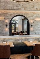 un restaurante con espejo, mesas y sillas en The Brownwood Hotel & Spa, en The Villages