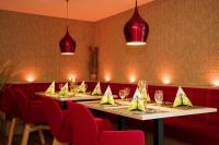 una fila di tavoli in un ristorante con sedie rosse di Thermen-Hotel Rottaler Hof a Bad Füssing