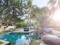 a swimming pool with palm trees in a backyard at Novotel Lombok Resort & Villas in Kuta Lombok