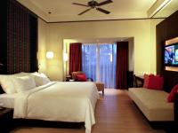 a bedroom with a large white bed and a couch at Novotel Lombok Resort & Villas in Kuta Lombok