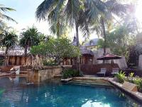 a swimming pool in front of a house with palm trees at Novotel Lombok Resort & Villas in Kuta Lombok