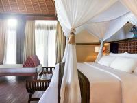 a bedroom with a canopy bed and a chair at Novotel Lombok Resort & Villas in Kuta Lombok