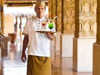 a man holding a tray with two drinks on it at Novotel Lombok Resort & Villas in Kuta Lombok