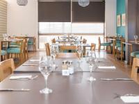 Un comedor con una mesa con copas de vino encima. en ibis Styles Geraldton, en Geraldton