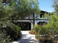 a white house with a driveway in front of it at Cottage with a big idyllic garden at the lake in Lacanau