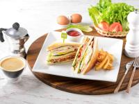 a plate with a sandwich and french fries on a table at Ibis Phuket Patong in Patong Beach