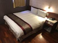 a bedroom with a large bed with white sheets at Gene Long Haiy Att Hotel in Chiayi City