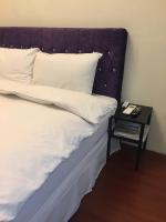 a bed with a purple headboard and a side table at Amicasa Guesthouse in Hualien City