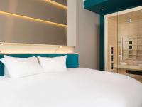 a bedroom with a white bed and a glass shower at ibis Styles Nivelles in Nivelles