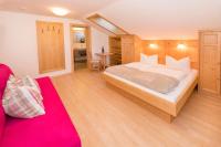 a bedroom with a large bed and a red couch at Das kleine, feine SONNWEND in Alpbach